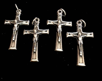 Op de afbeelding: Vier zilveren kruisbeelden met een figuur van Jezus Christus op elk. De kruisbeelden hebben een zwarte achtergrond en de inscriptie "INRI" bovenaan.