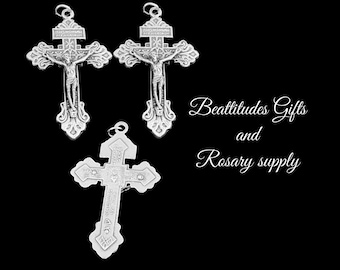 Op de afbeelding: Drie zilverkleurige kruisbeelden met een gedetailleerd ontwerp. De kruisbeelden tonen een figuur van Jezus Christus aan het kruis. De tekst "Beatitudes Gifts and Rosary supply" is zichtbaar in de afbeelding.