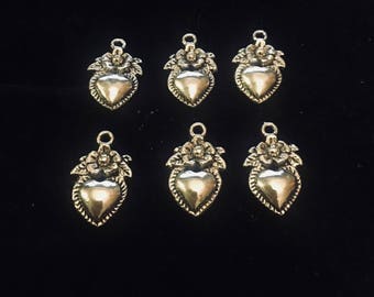 May include: Six silver heart-shaped charms with floral accents. Each charm has a loop at the top for attaching to jewelry or other crafts.