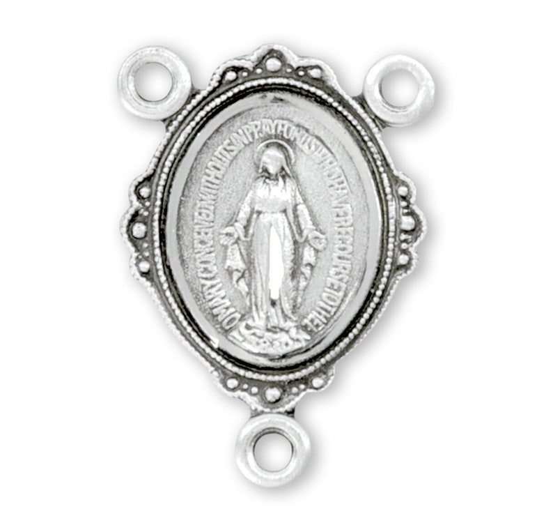 May include: Silver-toned metal rosary center piece featuring an oval-shaped image of the Virgin Mary with the words "OMNIA POSSIBILIA SUNT EI QUI CREDIT" around the image.