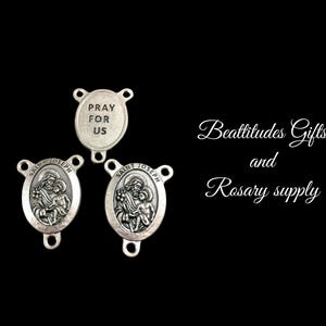 May include: Three silver-toned metal rosary charms. Two charms feature an image of Saint Joseph holding the baby Jesus. The third charm reads "Pray for Us".