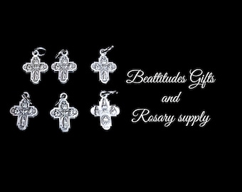 Op de afbeelding: Zes zilveren kruis hangers met ingewikkelde ontwerpen. De kruisen zijn gerangschikt in twee rijen van drie. De tekst "Beattitudes Gifts and Rosary supply" is zichtbaar in de rechterbovenhoek van de afbeelding.