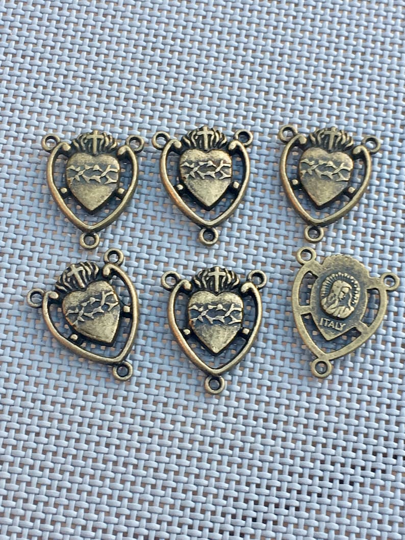 Puede incluir: Seis abalorios de metal dorado antiguo con un coraz&oacute;n con espinas y una cruz, y un abalorio con una representaci&oacute;n de la Virgen Mar&iacute;a y el texto "ITALIA".