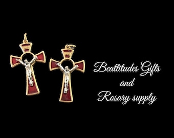 Op de afbeelding: Twee gouden kruisen met rode emaille en een zilverkleurige Jezusfiguur. De kruisen hebben een ronde opening in het midden. De tekst "Beatitudes Gifts and Rosary supply" is zichtbaar op de achtergrond.