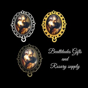 May include: Three oval pendants with portraits of a man with a white beard. The pendants have ornate frames in silver, gold, and bronze. The text "Beattitudes Gifts and Rosary supply" is written in cursive.