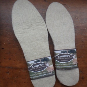 May include: Two pairs of beige wool insoles for boots. The insoles are made by Lambkin's and are 100% wool. The text on the insoles reads "Baa Boot 100% Wool Insoles Callicoon, NY" and "Get warm in winter...cool in summer www.WillowoolSheepFarm.com".