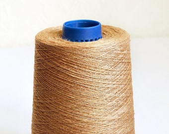 May include: A spool of brown thread wound around a plastic bobbin with a blue top.