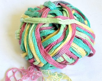 Puede incluir: Una bola de hilo en tonos de rosa, verde y amarillo. El hilo está hecho de un material suave y delicado, perfecto para tejer o hacer crochet.