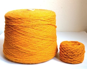 May include: Two skeins of bright yellow yarn. One is a large, cylindrical shape, and the other is a smaller, round ball. The yarn appears to be tightly wound and has a textured surface, suitable for knitting or crocheting projects.
