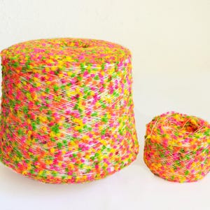 以下が含まれることがあります： 白を基調とし、ピンク、イエロー、グリーンの斑点が入った糸の巻き糸が2つ。大きな巻き糸は満タンで、小さな巻き糸は半分ほど巻かれている。