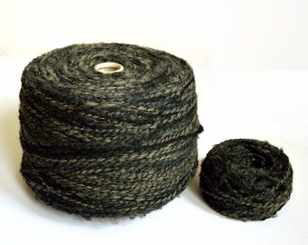 May include: A skein of dark green and black yarn, wound into a ball shape. The yarn is made of a blend of wool and other fibers.