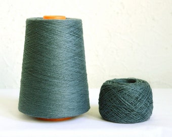 May include: Two spools of teal green yarn. One spool is on a cone and the other is a ball of yarn.