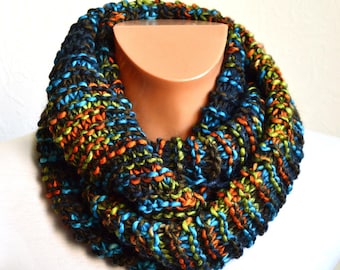 May include: A chunky knit infinity scarf in a vibrant mix of colors. The scarf features a blend of blue, orange, green, and brown yarns, creating a textured and eye-catching accessory. This cozy, handmade scarf is perfect for adding warmth and style.