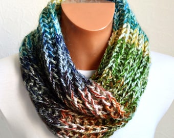 May include: A colorful knitted infinity scarf with a gradient of blue, green, brown, and white. The scarf is made with a chunky yarn and has a loose knit texture.