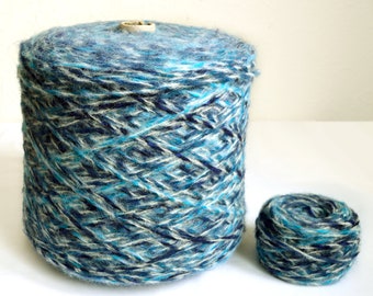 May include: A skein of yarn in shades of blue, white, and gray. The yarn is wound around a cardboard tube. A smaller skein of the same yarn is also shown.