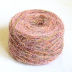 May include: A ball of yarn in shades of pink, orange, and green. The yarn appears soft and fluffy, ideal for knitting or crocheting projects. The colors are blended, creating a textured appearance.