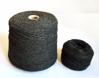 May include: Two spools of dark gray yarn. One spool is larger and the other is smaller.