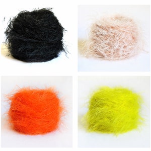 Puede incluir: Cuatro ovillos de lana en diferentes colores: negro, beige, naranja y amarillo. La lana es esponjosa y tiene una textura suave.