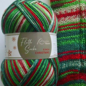 May include: A ball of Christmas-themed yarn with red, green, and white stripes next to a knitted sock in matching colours. The yarn label reads "Flotte Socke Christmas".