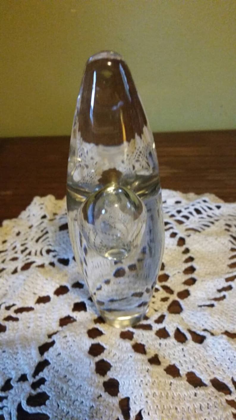 May include: A clear glass pipe with a round bowl and a long, narrow stem. The pipe is sitting on a white crocheted doily.