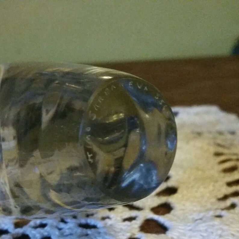 May include: Close-up of the bottom of a clear glass bottle with the text "S.I.M.R.A. EVA 350" etched into the glass.