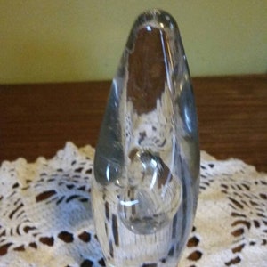 May include: A clear glass sculpture with a rounded, organic shape. The sculpture has a smooth, polished surface and appears to be hand-blown.