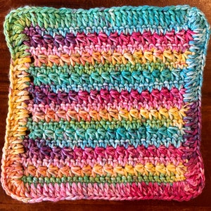 May include: A square, hand-crocheted item with a vibrant, multicoloured design. It features horizontal stripes of pink, yellow, green, and blue, with a textured stitch pattern. The edges are finished with a solid turquoise border.
