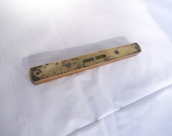 May include: A vintage level with a wooden body and brass end caps. The level has two bubble vials and is marked with the text "ARRIE WILSON". The brass shows signs of age and wear.