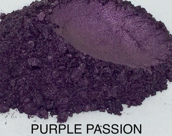 May include: A close-up of a pile of purple mica powder. The powder has a slight shimmer and is labeled "PURPLE PASSION #040-P".