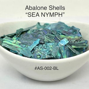 May include: A white bowl filled with iridescent abalone shell fragments. The shells have a mix of blue, green, and purple hues. Text on the image reads "Abalone Shells 'SEA NYMPH'" and "#AS-002-BL".