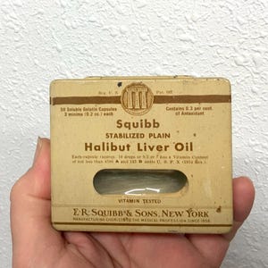 May include: Vintage Squibb Halibut Liver Oil box. The box is beige with brown text and a clear window. The text includes "Stabilized Plain" and "Vitamin Tested". The box contains 50 soluble gelatin capsules.