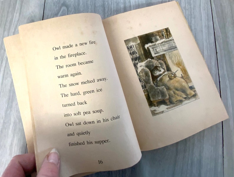 K&ouml;nnte beinhalten: Offenes Vintage-Kinderbuch mit Text und Illustration. Der Text lautet: &bdquo;Owl made a new fire in the fireplace.&ldquo; Die Illustration zeigt eine Eule in einem Stuhl in der N&auml;he eines Kamins. Die Seiten des Buches sind gealtert und haben einen hellbraunen Farbton.