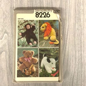 May include: A vintage Simplicity sewing pattern, featuring illustrations of stuffed animal designs: a monkey, lion, teddy bear, and dog. The pattern is labeled "8226" and "ONE SIZE". The cover is slightly worn, with a price tag in the upper right corner.