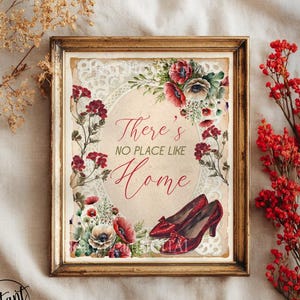 Może przedstawiać: Oprawiony wydruk z napisem "There's No Place Like Home". Grafika przedstawia czerwone buty na wysokim obcasie, kwiatowe akcenty i stylizację w stylu vintage. Rama jest w kolorze złotym.
