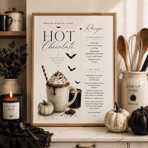 May include: A framed wall art print titled Hocus Pocus Cafe Hot Chocolate, featuring a recipe with ingredients and method, illustrated with a mug of hot chocolate, whipped cream, a striped straw, small pumpkins, bats, and a spider icon.