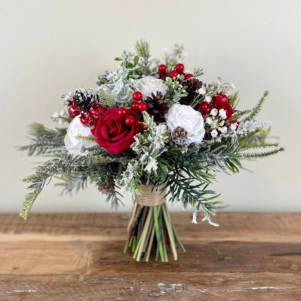 Weihnachtshochzeitsstrauß in Rot und Weiß, mit Tannenzapfen und schneebedecktem Evergreen für eine Winterhochzeit