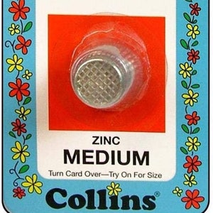 May include: A blue and white card with a red background shows a silver thimble with a grid pattern. The card reads "Safety Thimble" and "For Quilting Home Sewing Crafts". It also says "Ridge on top holds needle safely & helps prevent slipping". The card also says "Zinc Medium" and "Turn Card Over-Try On For Size". The bottom of the card reads "Collins".
