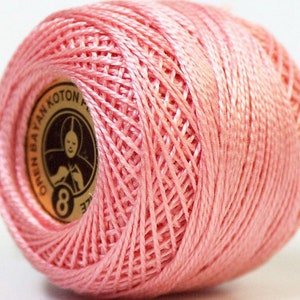 May include: A pink ball of yarn with a gold label that says "Oren Bayan Koton 8"