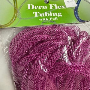 May include: A package of Deco Flex Tubing with Foil in a vibrant magenta color. The packaging indicates the tubing is 8mm x 30 yards. The tubing is tightly coiled and appears to be made of a mesh-like material with a metallic sheen.