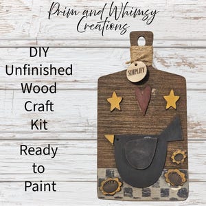 May include: A wooden DIY craft kit shaped like a cutting board, featuring a dark bird, stars, and a heart. The text "Prim and Whimsy Creations", "DIY Unfinished Wood Craft Kit Ready to Paint", and "SIMPLIFY" are visible.