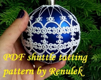 May include: A blue Christmas ornament covered in white crocheted lace. The ornament is being held in a hand. The text "PDF shuttle tatting pattern by Renulek" is visible below the ornament.