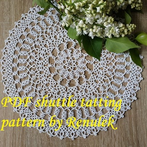 May include: White crochet doily with a circular pattern. The doily is on a wooden surface. The text "PDF shuttle tatting pattern by Renulek" is visible in the bottom right corner of the image.