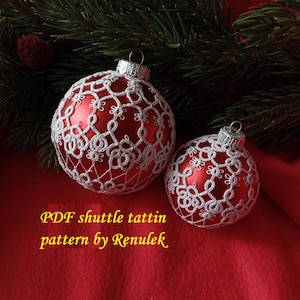 May include: Two red Christmas ornaments covered in white lace. The ornaments are on a red background with a green pine branch in the background. The text "PDF shuttle tatting pattern by Renulek" is at the bottom of the image.