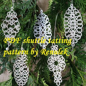 May include: Five white, intricately designed shuttle tatting ornaments hang against a backdrop of green foliage. The ornaments have various shapes, including teardrop and circular designs. Text in yellow reads "PDF shuttle tatting pattern by Remlek."