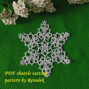 May include: A white, intricately designed snowflake made with shuttle tatting, set against a vibrant green background. The text "PDF shuttle tatting pattern by Renulek" is displayed in yellow. Delicate white flowers are in the upper left corner.
