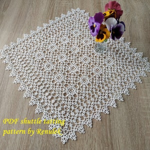 May include: White lace doily with a delicate pattern, featuring a scalloped edge. A vase with purple and yellow flowers sits on top of the doily. The text "PDF shuttle tatting pattern by Renulek" is visible in the bottom left corner.