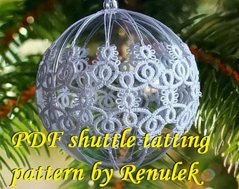 May include: A white crocheted ornament in the shape of a sphere, hanging from a Christmas tree. The ornament is made with a delicate lace pattern and is surrounded by green pine needles. The text "PDF shuttle tatting pattern by Renulek" is visible below the ornament.
