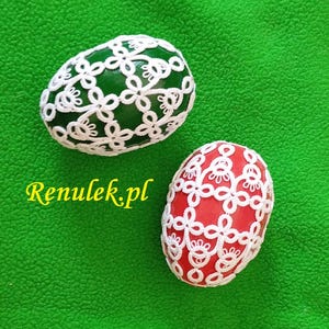 May include: Two Easter eggs decorated with white lace. One egg is green and the other is red.