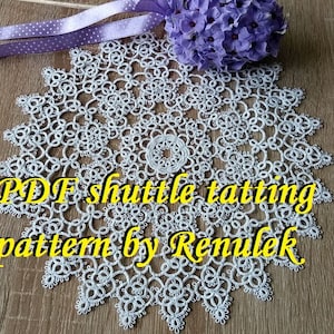 May include: White crochet doily with a delicate, intricate design. The doily is made with a shuttle tatting technique. The text "PDF shuttle tatting pattern by Renulek" is written in yellow letters on the doily.