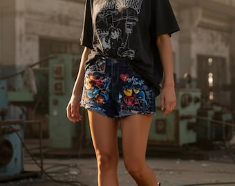 May include: A person wearing a black graphic t-shirt and denim shorts. The shorts are decorated with colorful illustrations and the text "Taylor Swift". The person is wearing brown boots.